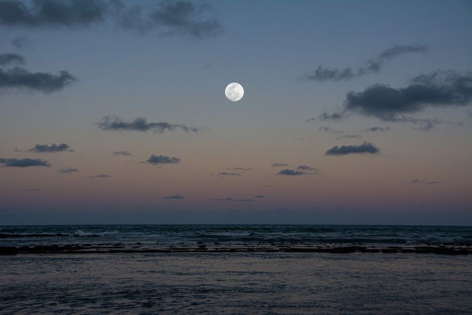 Serene view of a full moon over Arraial d'Ajuda beach during twilight, Bahia, Brazil.