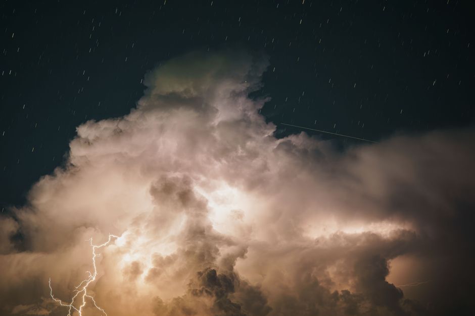 A captivating night sky with dramatic lightning illuminating large thunderstorm clouds.