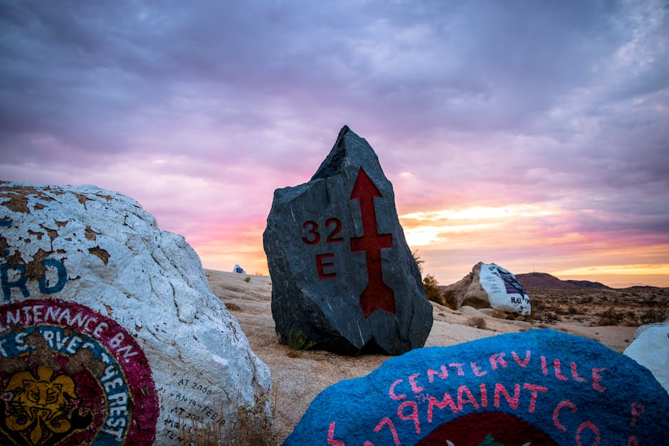 Painted rocks with directional symbols under a colorful sunset in Fort Irwin, CA desert.