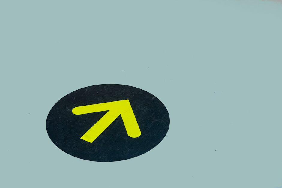 Minimalist image of a yellow arrow on a blue floor indicating direction, ideal for navigation themes.