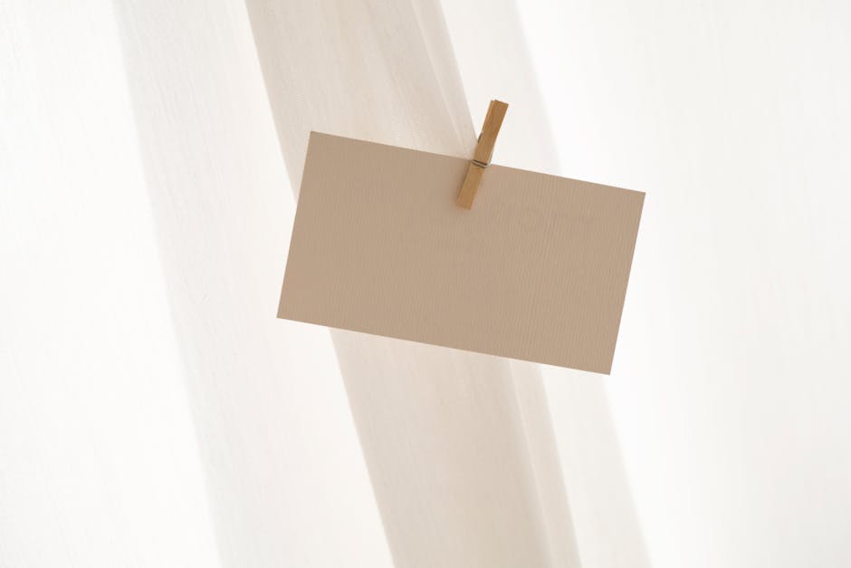A neutral, minimalist blank card secured by a clothespin against a soft backdrop.