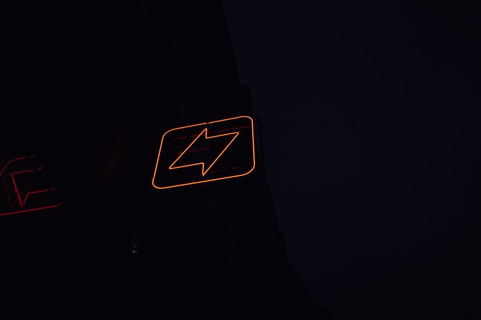 A glowing neon lightning bolt sign against a dark night background, symbolizing energy and electricity.