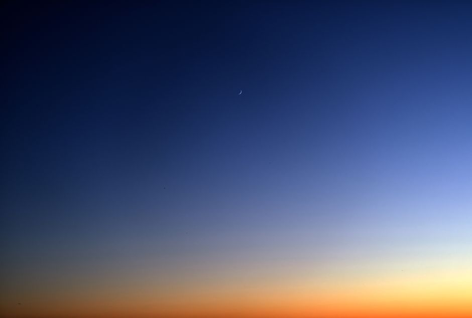 Beautiful twilight sky with a crescent moon and serene gradient of colors.