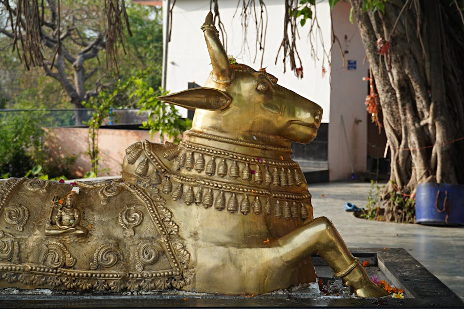 Side view of a golden Nandi bull statue at a Hindu temple, draped in intricate ornaments.
