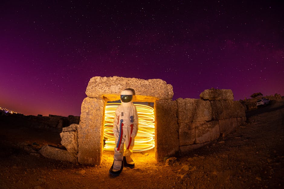 Astronaut in a rocky landscape with swirling lights under a starry night sky, evoking mystery and exploration.