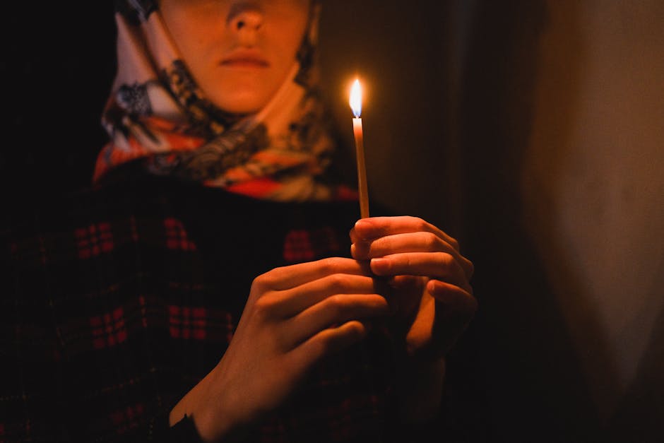 A person holds a candle in a dark setting, creating a serene and intimate atmosphere.