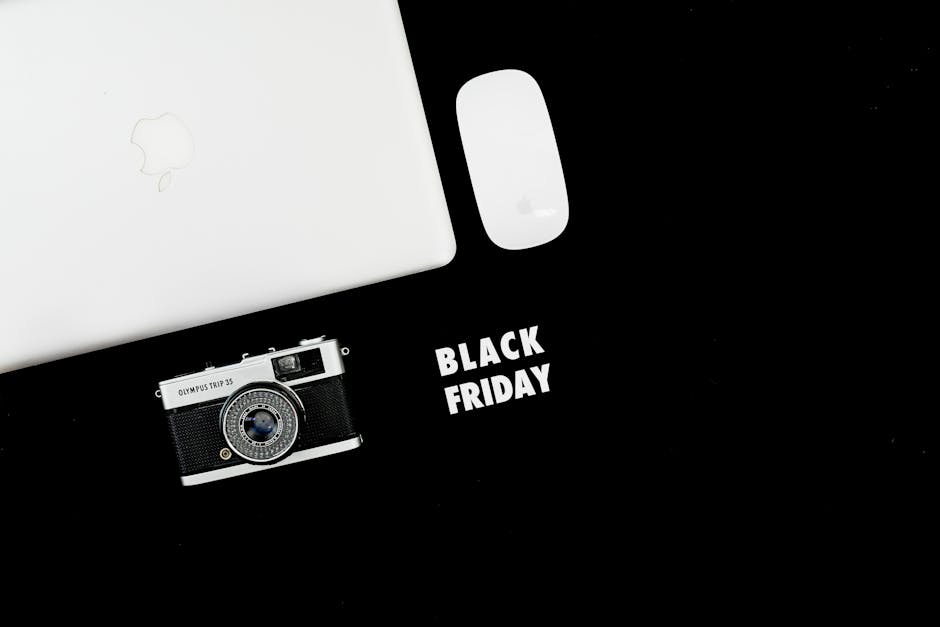 Stylish flat lay of laptop, camera, and mouse with Black Friday text.