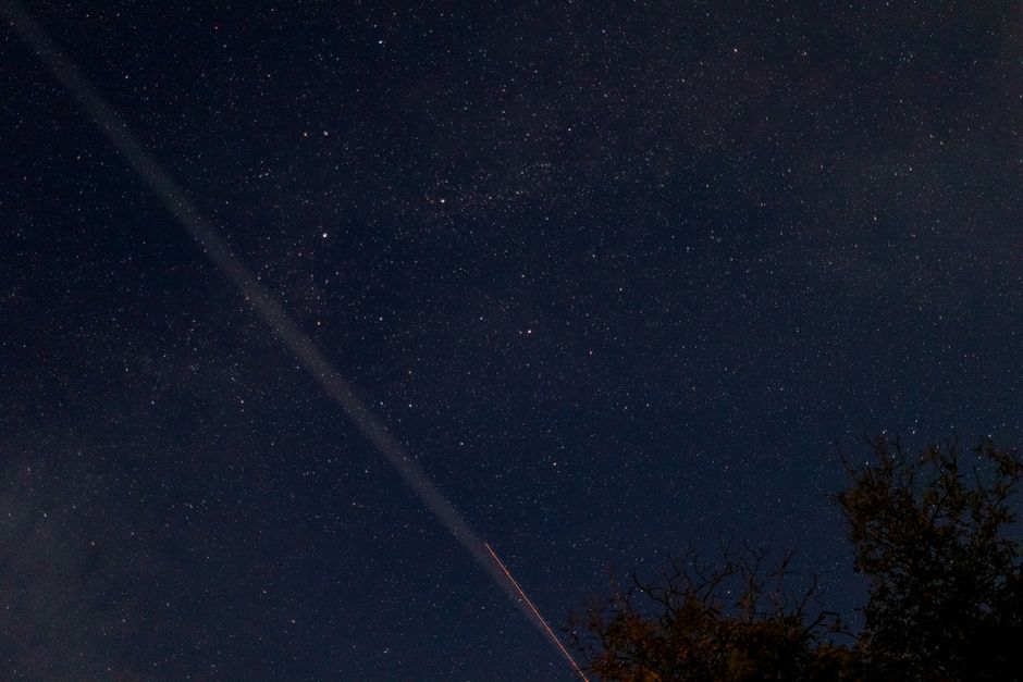A breathtaking view of a starry night sky with a visible meteor streaking across, captured outdoors.