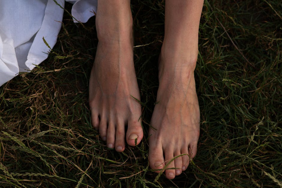 Close-up of a woman's bare feet in the grass, conveying a natural and serene summer vibe.