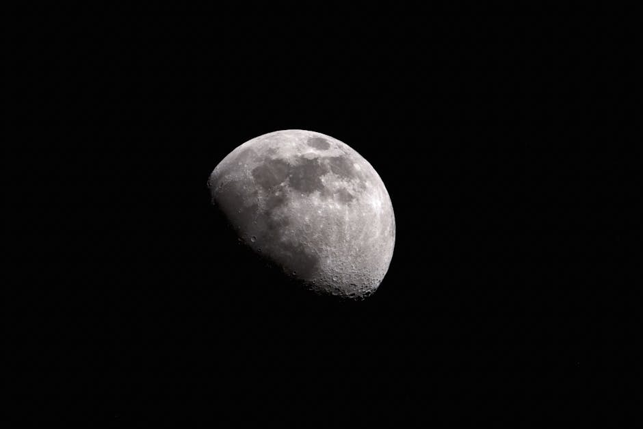 Black and white of moon with craters glowing on black sky at night