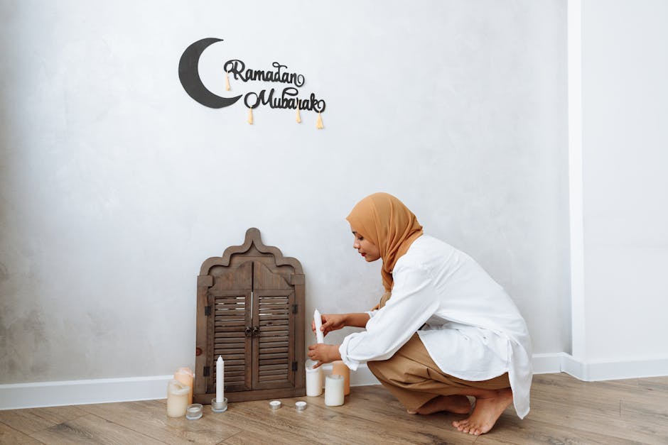 A woman in a hijab lights decorative candles for Ramadan indoors.