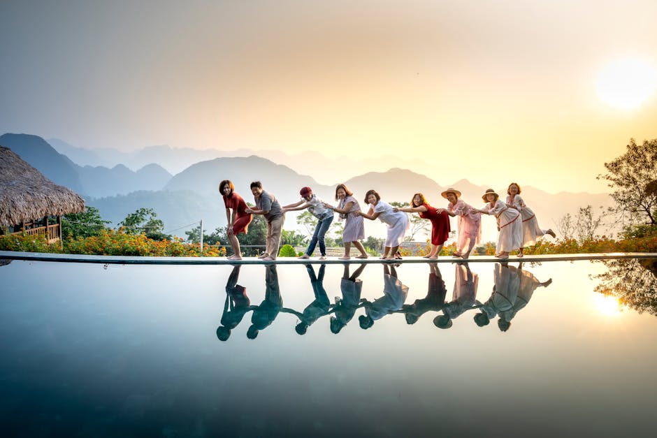 Group of happy people standing in chain above still water of lake and having fun in summer evening