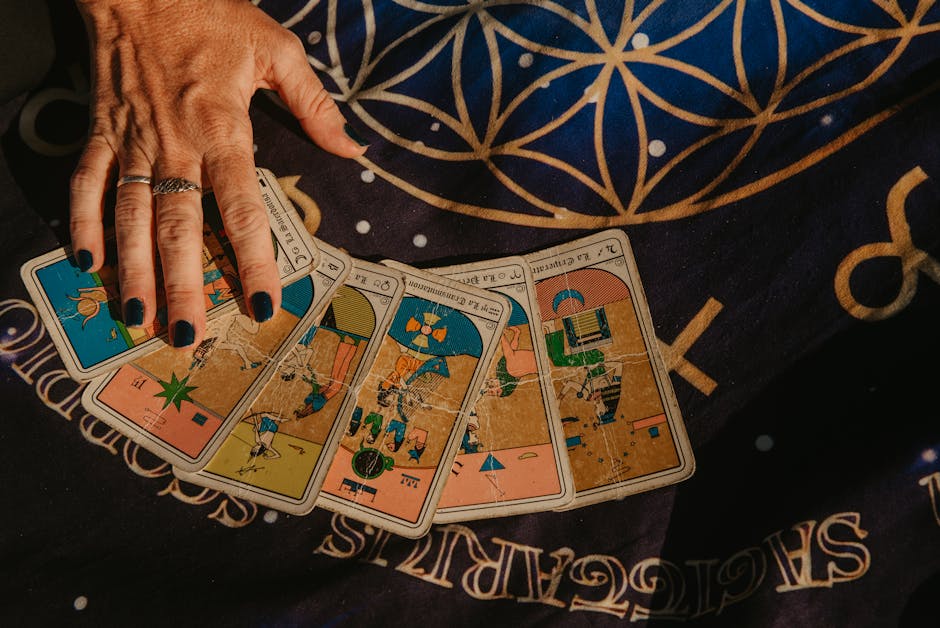 A hand arranging tarot cards on a star-studded cloth, showcasing divination symbolism.