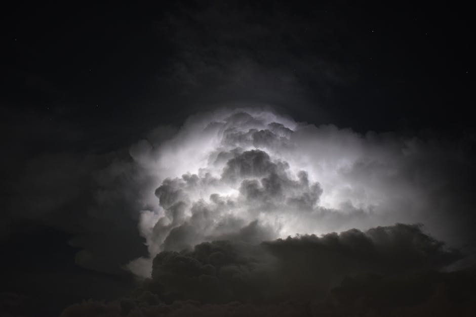 Powerful lightning illuminates dark storm clouds at night, creating a dramatic and mysterious sky.