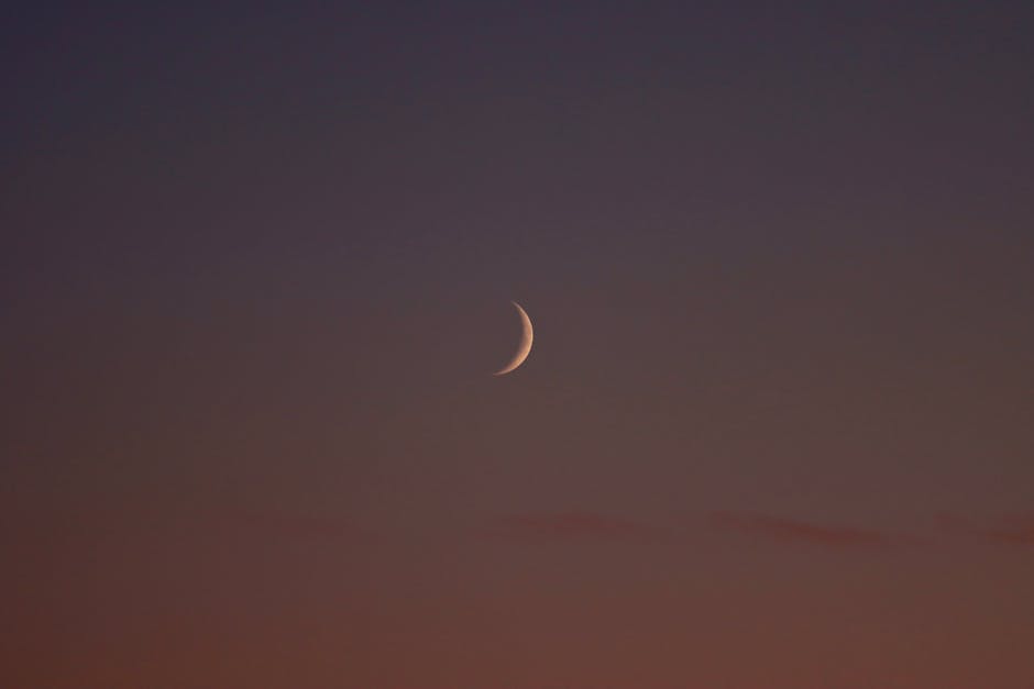 A beautiful crescent moon glows softly in a dusky sky over Jönköping, Sweden.