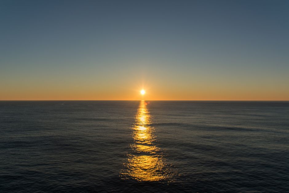 Serene ocean sunset with vibrant hues and golden reflections on the water.
