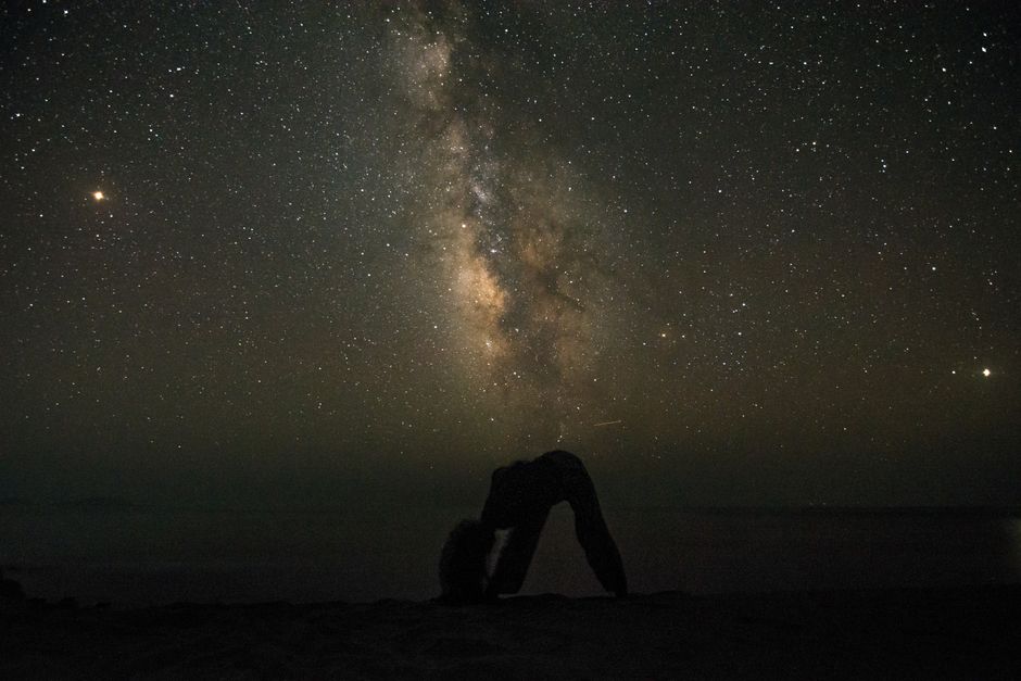 A stunning silhouette of a person beneath the vibrant Milky Way in a starry night sky.