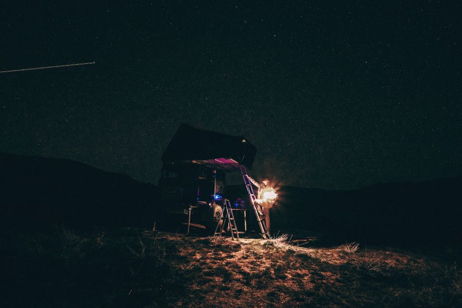 A scenic night camp setting with a tent, campfire, and starry sky, ideal for adventure and outdoor exploration themes.