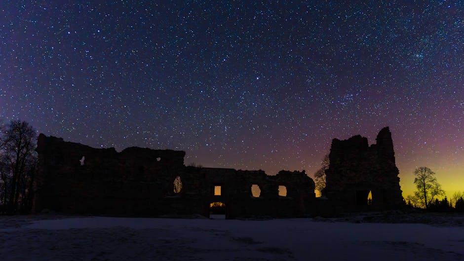 Silhouette of ancient ruins under a vivid starry sky at twilight.
