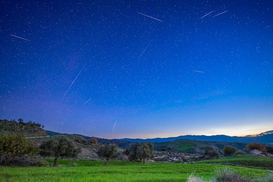 Beautiful night sky with stars over grassy fields and hills, showcasing nature's beauty.