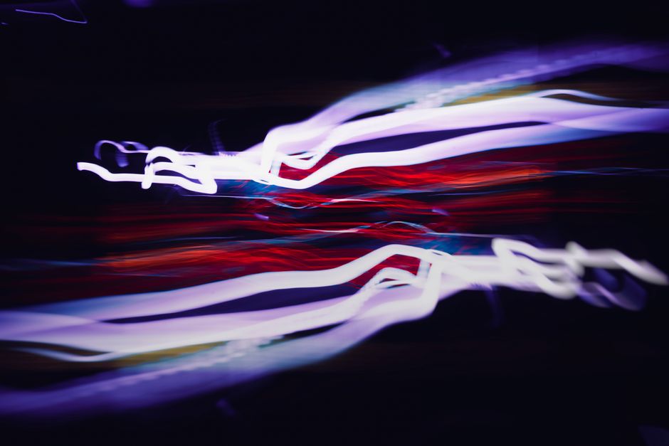 Vibrant light streaks in motion against a dark backdrop create a dynamic abstract effect.