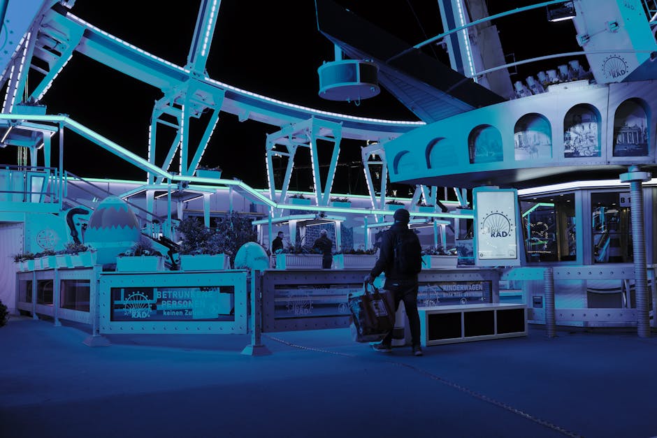 A person walking past a brightly lit Ferris wheel at night in Hamburg, Germany.