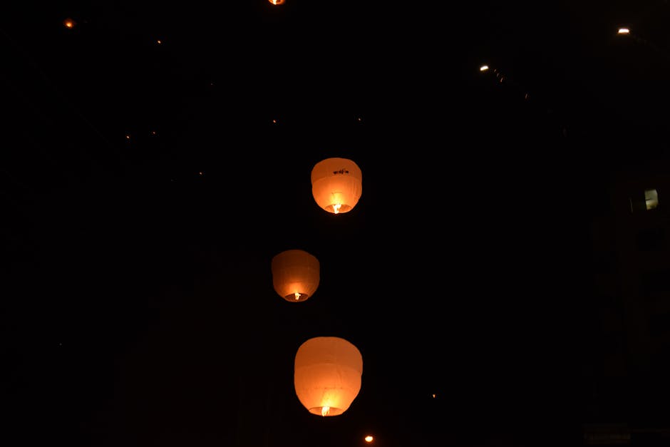 Sky lanterns glowing warmly as they ascend into the night sky.