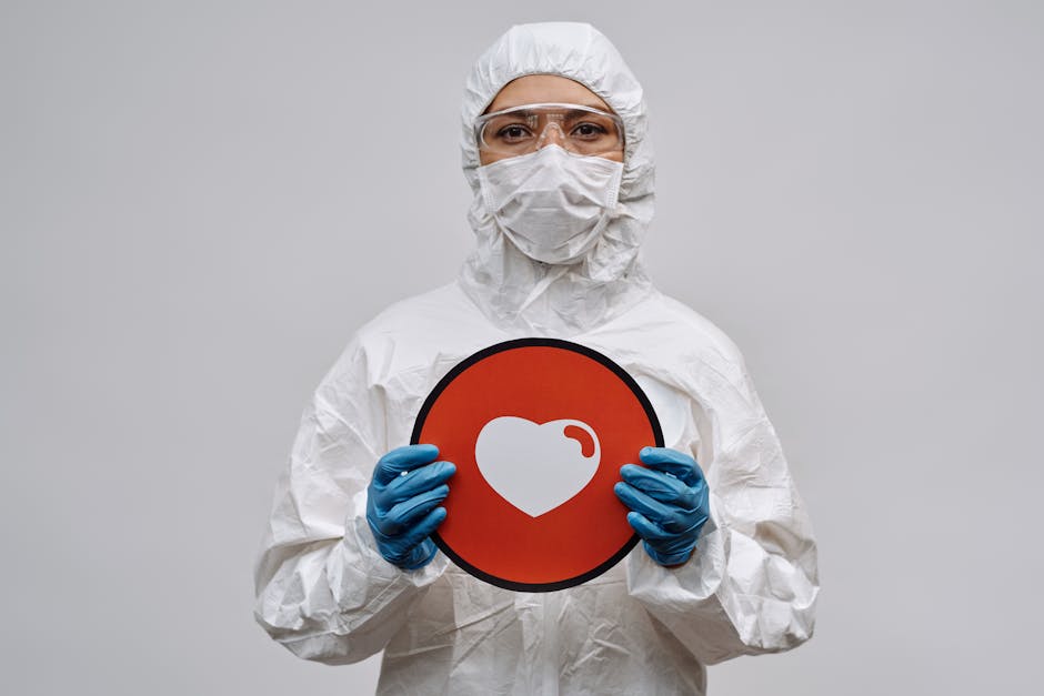 Individual in protective gear holding a heart symbol sign conveying care and protection.