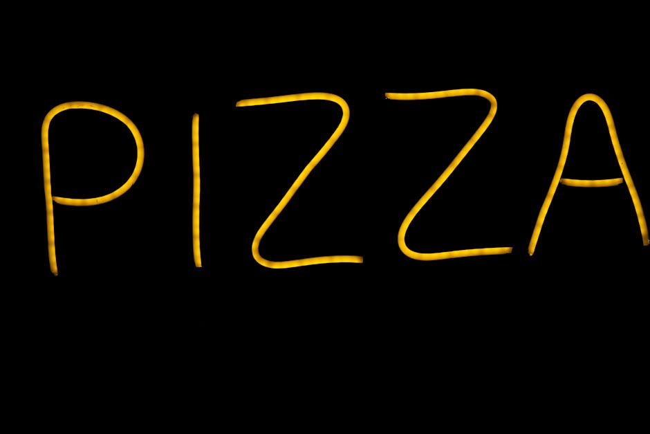 Glowing yellow neon pizza sign on a black background in Porto, Portugal.