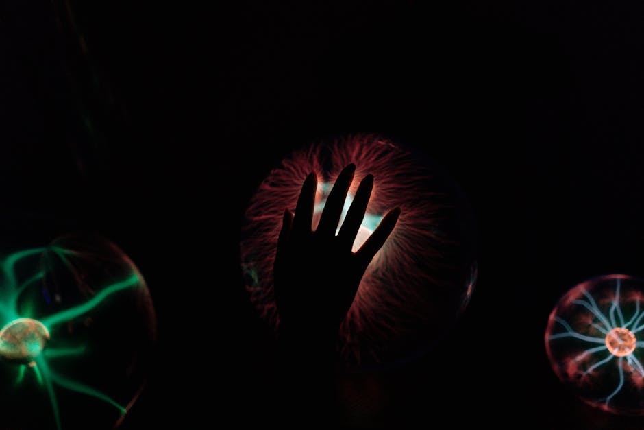 Silhouette of a hand interacting with a glowing plasma ball, illustrating electric waves.