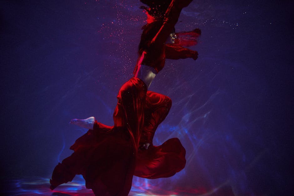 A captivating image of a woman floating underwater in a flowing red dress, creating a dramatic and surreal scene.
