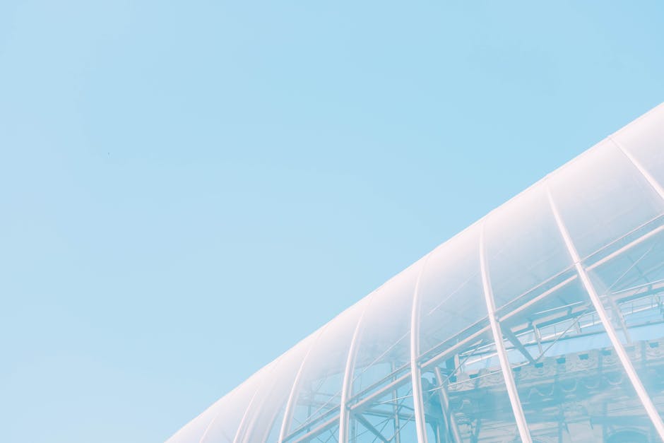 Low angle view of a modern glass building under a clear blue sky, showcasing architectural elegance.