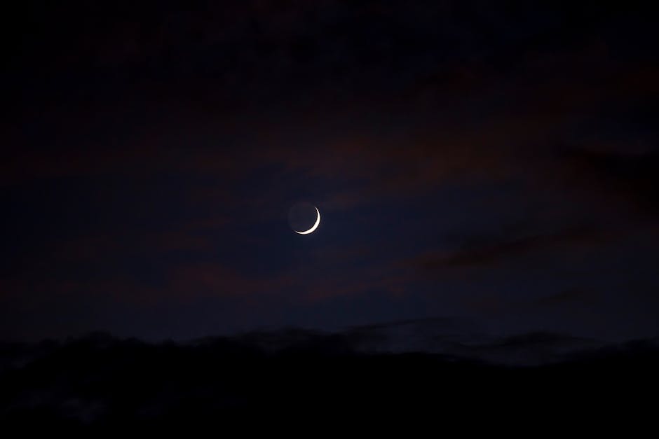 A tranquil crescent moon among soft clouds in a peaceful night sky.