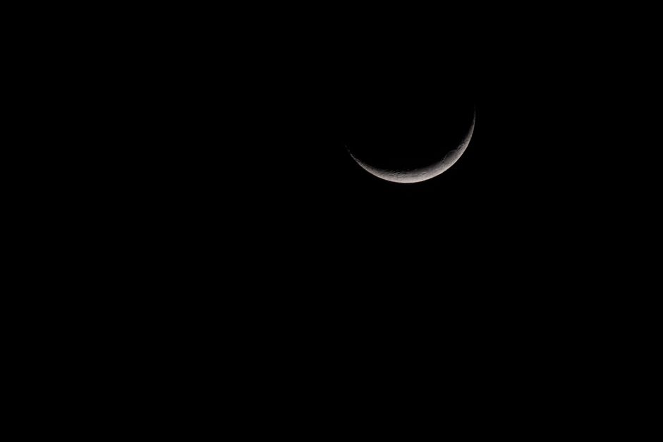 A beautiful crescent moon casting a serene glow against a dark night sky.