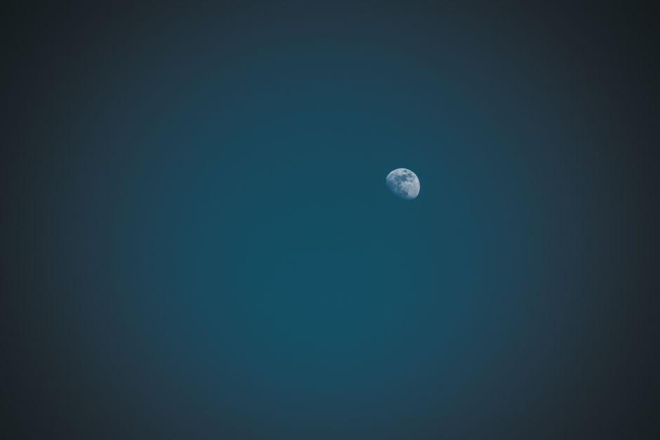 Capture of the moon against a deep blue night sky, highlighting its surface features.