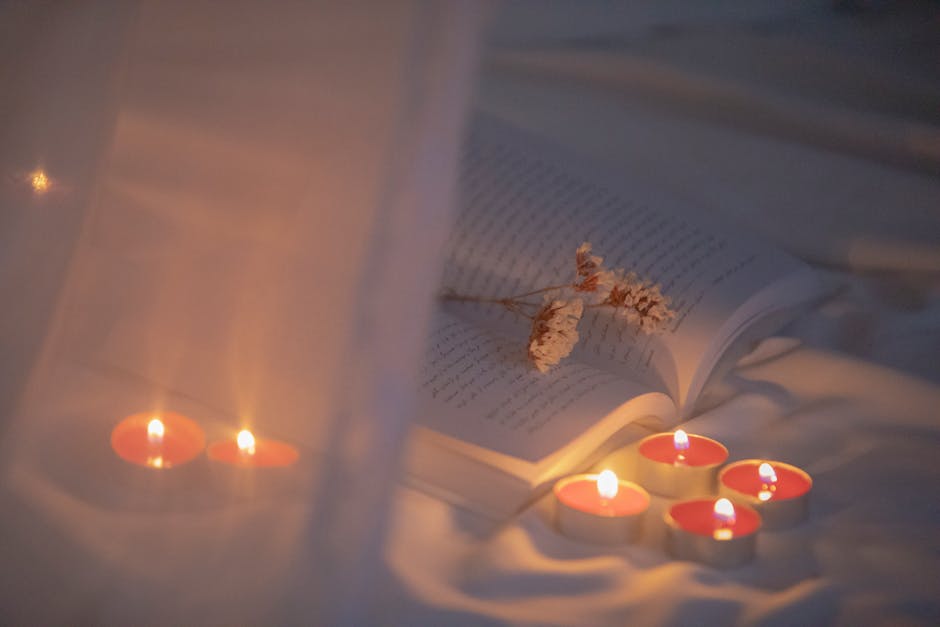 Warm and serene ambiance with open book and tea light candles on white cloth.
