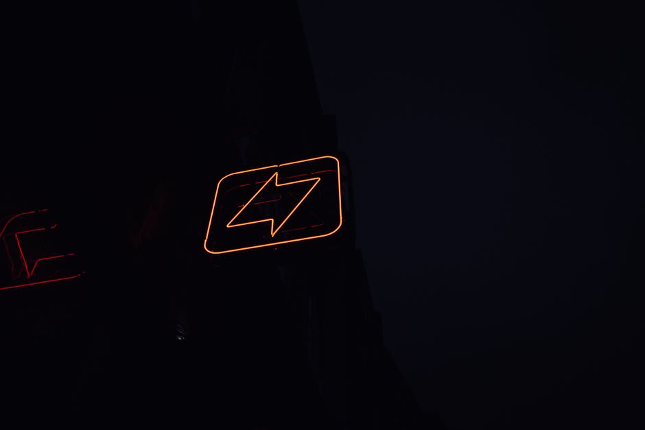 A glowing neon lightning bolt sign against a dark night background, symbolizing energy and electricity.