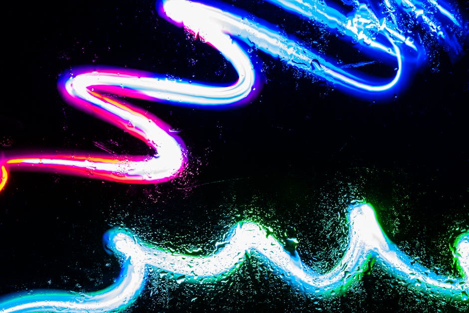 Dynamic neon light patterns against a black background with visible water droplets.